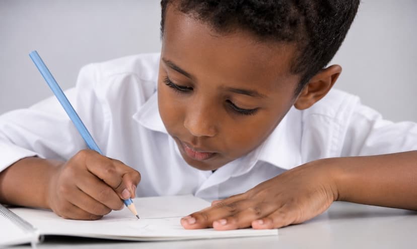A young student focused on learning and writing in a notebook